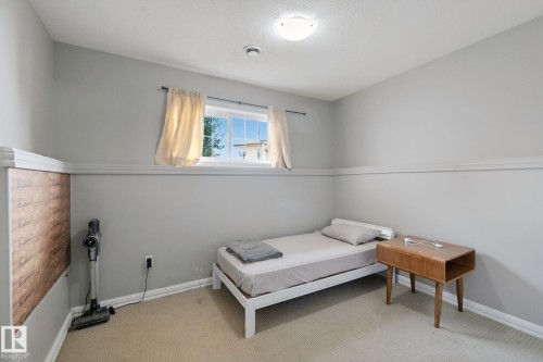 Carpeted room with light gray walls, a window with exterior visibility, a wall-mounted light fixture, and crown molding - 16807 78 Street Nw, Edmonton, AB 