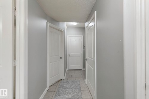 Hallway featuring tile flooring, neutral wall tones, and multiple panel doors - 16807 78 Street Nw, Edmonton, AB 