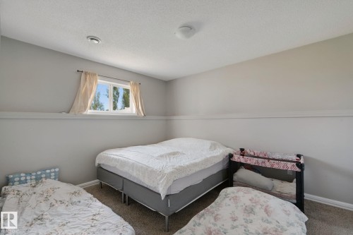 Wall-to-wall carpeting with a neutral finish, featuring a window with a valance and ceiling-mounted lighting - 16807 78 Street Nw, Edmonton, AB 