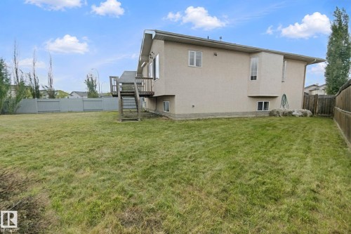 Expansive grassy yard featuring a wood deck with stairs, a privacy fence, and multiple windows - 16807 78 Street Nw, Edmonton, AB 