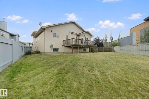Spacious backyard featuring a wooden deck, mature trees, and privacy fencing - 16807 78 Street Nw, Edmonton, AB 