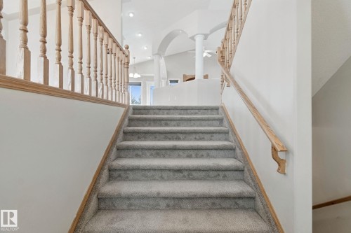 Carpeted staircase with wooden handrails and balusters - 16807 78 Street Nw, Edmonton, AB 