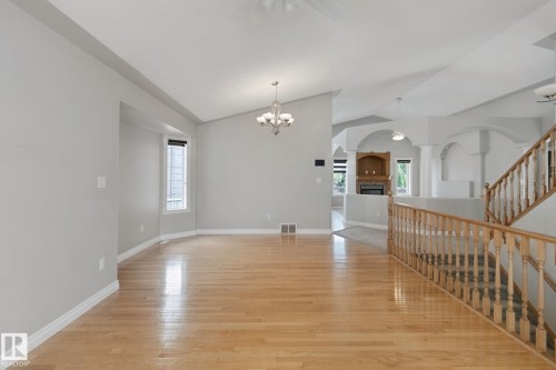Vaulted ceilings, wood-finish flooring, staircase with wood railing, recessed fireplace with built-in shelving, and arched architectural details - 16807 78 Street Nw, Edmonton, AB 