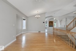 Vaulted ceilings, wood-finish flooring, staircase with wood railing, recessed fireplace with built-in shelving, and arched architectural details - 