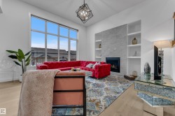 Expansive window offering abundant natural light, a built-in fireplace with a light-toned stone surround, integrated shelving, and wood-finish flooring - 