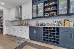 Kitchen featuring dual-tone cabinetry, a tile backsplash, light countertops, and wood-finish flooring - 