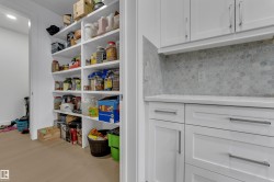 White shaker cabinetry with bar pull hardware, hexagon tile backsplash, and light-toned countertops - 