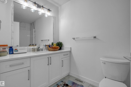 White shaker cabinetry with chrome hardware, a large vanity mirror, and a modern vanity light fixture - 1409 Graydon Hill Way Sw, Edmonton, AB 