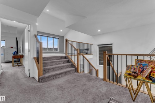 Carpeted stairs with wood-finish handrails and black metal spindles, recessed ceiling lighting, and expansive window with horizontal blinds - 1409 Graydon Hill Way Sw, Edmonton, AB 