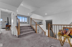 Carpeted stairs with wood-finish handrails and black metal spindles, recessed ceiling lighting, and expansive window with horizontal blinds - 