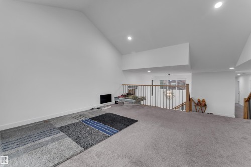 Carpeted loft space featuring a vaulted ceiling with recessed lighting and a wood-tone railing with black spindles - 1409 Graydon Hill Way Sw, Edmonton, AB 