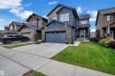 Multi-level residence featuring a stone and siding exterior, an attached garage, a paved driveway, and a front lawn - 1409 Graydon Hill Way Sw, Edmonton, AB 