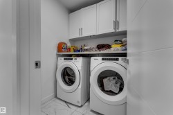 Laundry area featuring white cabinetry, a built-in shelf, and marble-look tile flooring - 