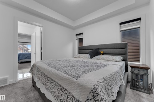 Tray ceiling with recessed lighting, plush carpet flooring, two windows with blinds, and a solid core door with modern hardware - 1409 Graydon Hill Way Sw, Edmonton, AB 