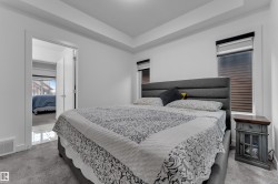 Tray ceiling with recessed lighting, plush carpet flooring, two windows with blinds, and a solid core door with modern hardware - 