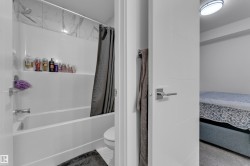 Tub and shower combination with white surround, integrated shelving, and a decorative tile accent wall - 