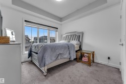 Tray ceiling with recessed lighting, large window with roller shade, neutral carpeting, and a white interior door - 