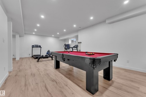 Spacious room featuring wood-finish flooring, recessed lighting, and bright white walls - 1409 Graydon Hill Way Sw, Edmonton, AB 