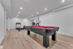 Spacious room featuring wood-finish flooring, recessed lighting, and bright white walls - 