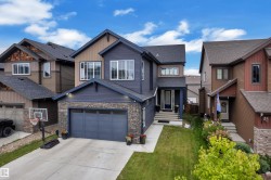 Two-story residence featuring a stone-clad garage, siding exterior, attached garage, concrete driveway, and a covered front entry - 
