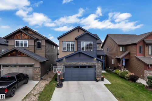 Multi-level property with dark blue and brown siding, stone accents, two-car garage, and concrete driveway - 1409 Graydon Hill Way Sw, Edmonton, AB 
