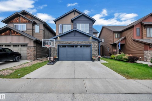 Two-story exterior with a stone facade, a two-car garage, and a concrete driveway - 1409 Graydon Hill Way Sw, Edmonton, AB 