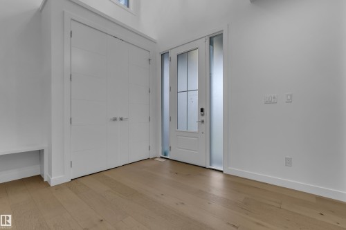 Wide plank wood-finish flooring, built-in storage bench, and a modern entry door with frosted sidelights - 1409 Graydon Hill Way Sw, Edmonton, AB 