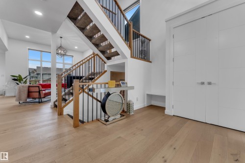 Hardwood-finish flooring, staircase with wood handrails and black balusters, recessed lighting, white panel doors, and large picture windows - 1409 Graydon Hill Way Sw, Edmonton, AB 