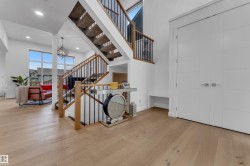 Hardwood-finish flooring, staircase with wood handrails and black balusters, recessed lighting, white panel doors, and large picture windows - 