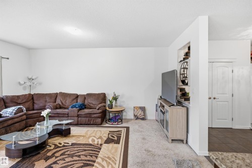 Carpeted living area with white walls and a built-in shelving unit - 1523 36 Avenue Nw, Edmonton, AB 