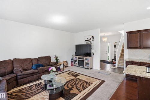 Light-colored walls, carpeted living area, dark wood-finish flooring, kitchen with dark wood-finish cabinetry, and light-toned countertop - 1523 36 Avenue Nw, Edmonton, AB 