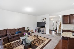 Light-colored walls, carpeted living area, dark wood-finish flooring, kitchen with dark wood-finish cabinetry, and light-toned countertop - 