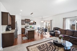 Open-concept living space featuring wood-finish flooring, recessed lighting, a kitchen island with stone countertops, and dark wood cabinetry - 
