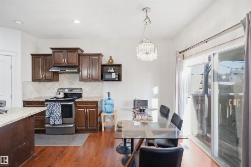 Kitchen and dining area featuring wood-finish flooring, dark wood cabinetry, light-toned countertops, and a white tile backsplash - 1523 36 Avenue Nw, Edmonton, AB 