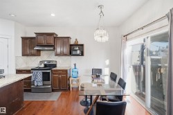 Kitchen and dining area featuring wood-finish flooring, dark wood cabinetry, light-toned countertops, and a white tile backsplash - 