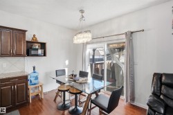 Hardwood-finish flooring, built-in cabinetry, granite-look countertops, tiled backsplash, and sliding glass door - 