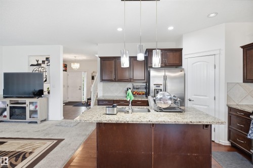 Kitchen island with granite countertop, wood-finish cabinetry, stainless steel appliances, and pendant lighting - 1523 36 Avenue Nw, Edmonton, AB 