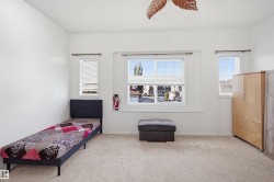 Carpeted room featuring multiple windows with blinds, a ceiling fan, and white walls - 