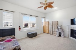 Carpeted flooring, multiple windows with blinds, ceiling fan, and a fireplace with a mantel - 