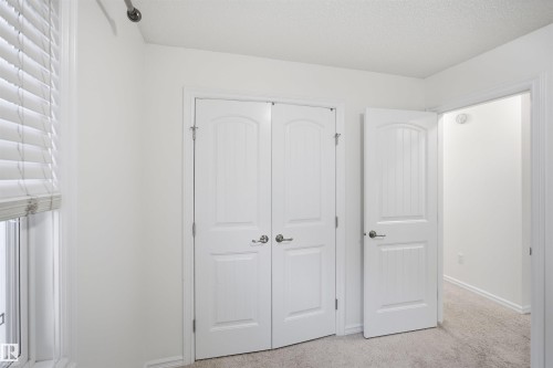 White interior walls, white paneled doors with brushed nickel hardware, window with white blinds, and light-colored carpet flooring - 1523 36 Avenue Nw, Edmonton, AB 