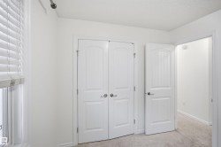 White interior walls, white paneled doors with brushed nickel hardware, window with white blinds, and light-colored carpet flooring - 