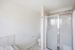 Tiled shower enclosure with sliding frosted glass door, white toilet, and light-toned floor tile - 
