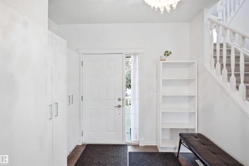 Entryway featuring a paneled door with sidelight, wood-finish flooring, built-in storage cabinetry with brushed nickel hardware, and a carpeted staircase with white balusters - 1523 36 Avenue Nw, Edmonton, AB 