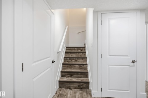 Wood-finish flooring extending to staircase treads, white paneled doors, and a white handrail - 1523 36 Avenue Nw, Edmonton, AB 