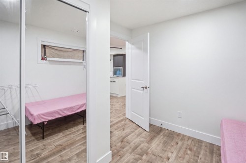 Wood-finish flooring, white interior doors, and a mirrored closet door - 1523 36 Avenue Nw, Edmonton, AB 