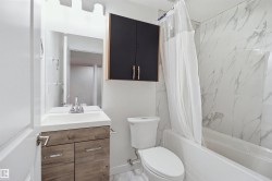 Bathroom featuring a wood-finish vanity with an integrated sink, a wall-mounted medicine cabinet, and a tiled shower-tub combination - 