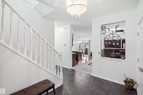 Entryway featuring dark tile flooring, a white spindle staircase, and a decorative wall cutout - 1523 36 Avenue Nw, Edmonton, AB 