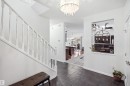 Entryway featuring dark tile flooring, a white spindle staircase, and a decorative wall cutout - 1523 36 Avenue Nw, Edmonton, AB 