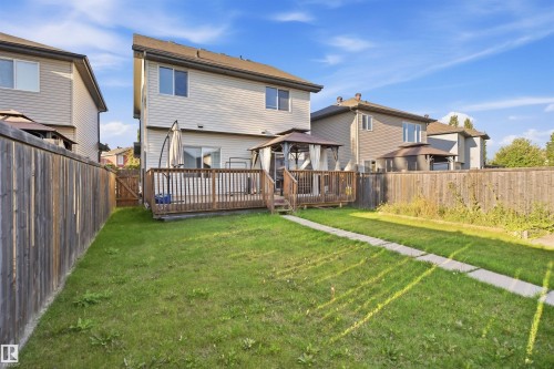 Expansive fenced backyard with a wood deck, a covered gazebo, and a paved pathway - 1523 36 Avenue Nw, Edmonton, AB 
