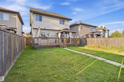 Expansive fenced backyard with a wood deck, a covered gazebo, and a paved pathway - 